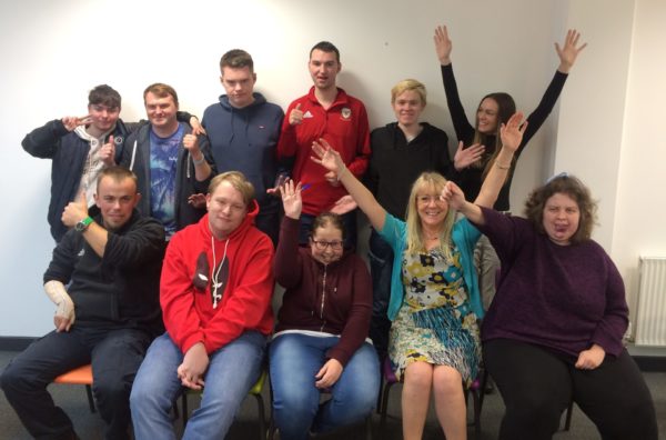 A happy group of project participants and staff posing for a photo together, some with their hands in the air.